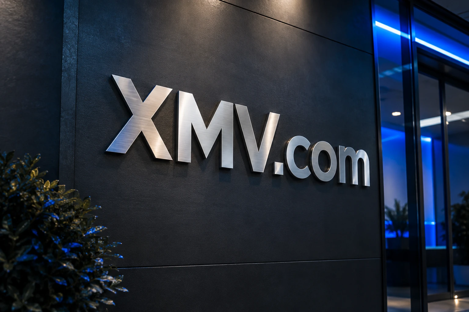 XMV.com in brushed metal on a dark architectural wall with cobalt light